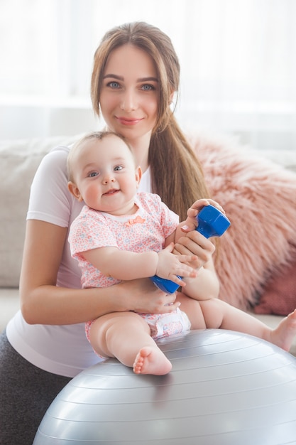 Jeune jolie mère travaillant avec son petit enfant à la maison