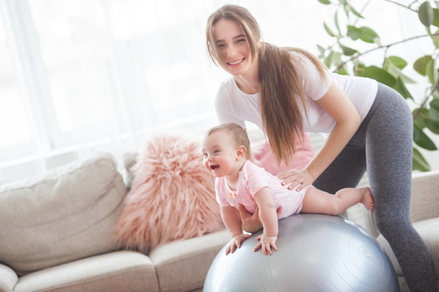 Jeune jolie mère travaillant avec son petit enfant à la maison