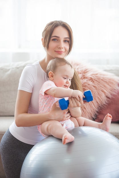 Jeune jolie mère travaillant avec son petit enfant à la maison