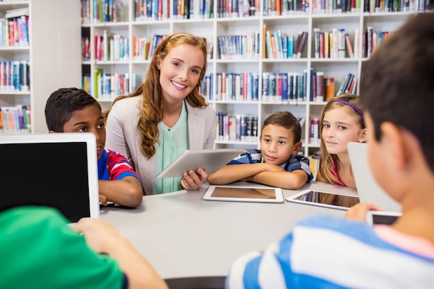 Jeune jolie professeur ayant leçon aux enfants avec leur tablette