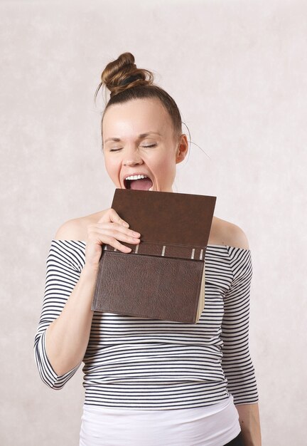 Une jeune jolie vieille femme mordant un livre