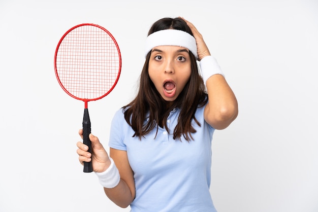 Jeune joueur de badminton femme sur mur blanc isolé avec expression surprise
