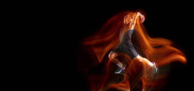 Jeune joueur de basket-ball d'Asie de l'Est en action et saut dans une lumière mixte sur fond de studio sombre