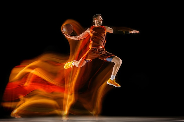 Jeune joueur de basket-ball caucasien sur fond sombre en lumière mixte