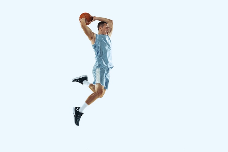 Photo jeune joueur de basket-ball caucasien de haut vol de l'équipe en mouvement d'action en saut isolé