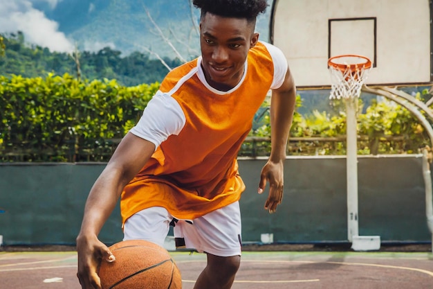 Un jeune joueur de basket-ball dribble le ballon sur le terrain de basket-bal en action.