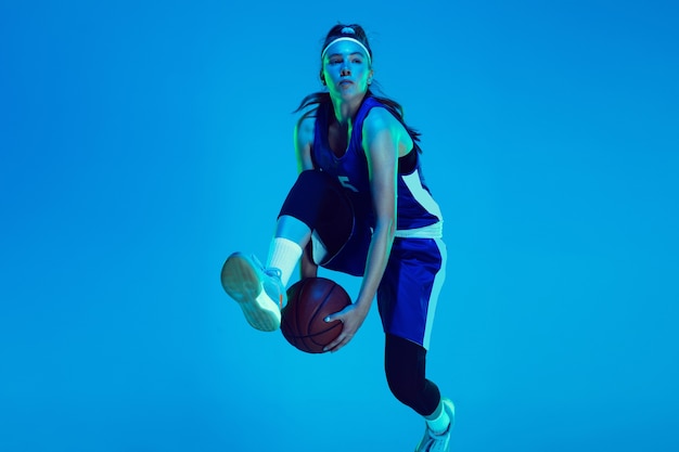 Jeune Joueur De Basket-ball Féminin Caucasien Isolé Sur Fond Bleu Studio à La Lumière Du Néon