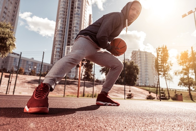 Jeune joueur. Faible angle d'un beau jeune homme tenant un ballon tout en jouant au basket