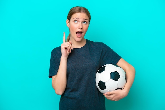 Jeune joueur de football femme isolée sur fond bleu pensant à une idée pointant le doigt vers le haut