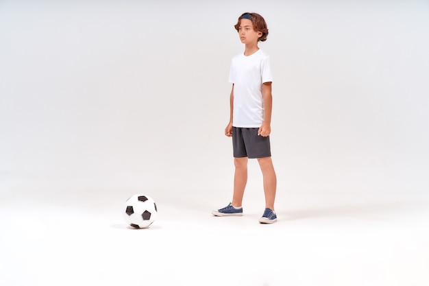 Jeune joueur de football sur toute la longueur d'un adolescent jouant tout en jouant au football isolé