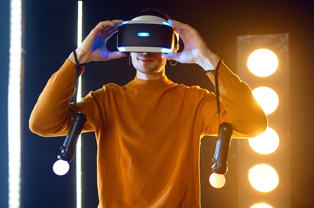 Jeune joueur joue au jeu en utilisant un casque de réalité virtuelle et une manette de jeu dans un cube lumineux