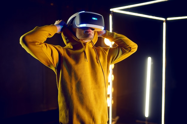 Jeune joueur joue au jeu en utilisant un casque de réalité virtuelle et une manette de jeu dans un cube lumineux