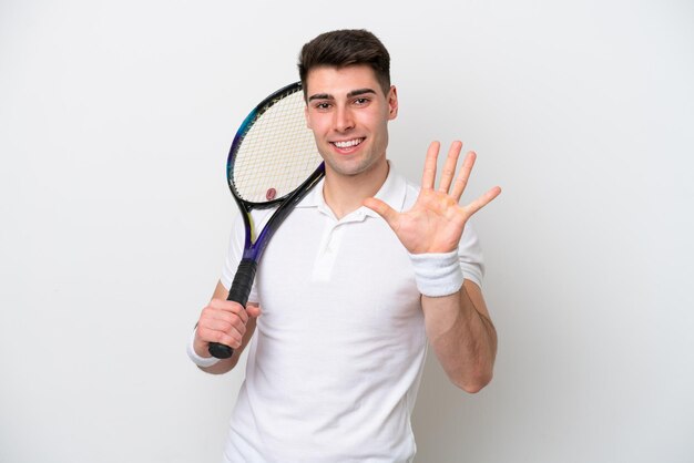 Jeune joueur de tennis homme isolé sur fond blanc comptant cinq avec les doigts