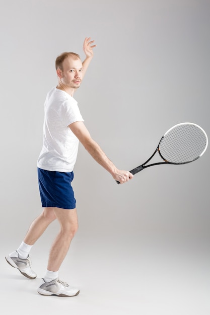 Le jeune joueur de tennis joue au tennis sur un gris