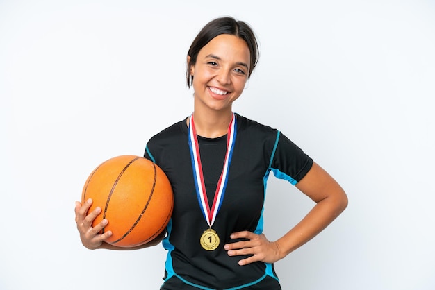 Jeune joueuse de basket-ball isolée sur fond blanc posant avec les bras à la hanche et souriante