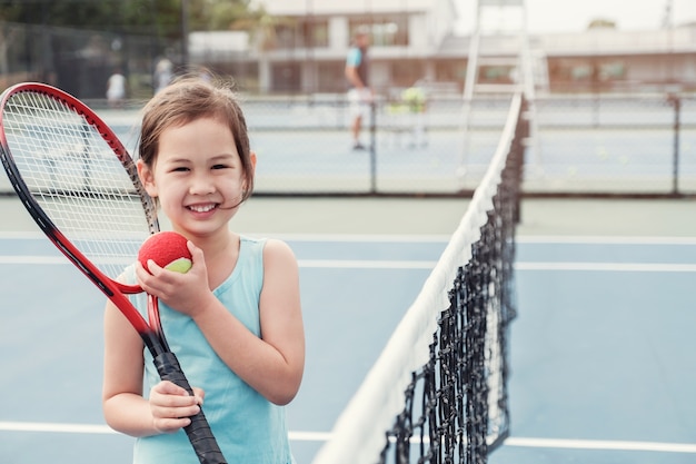 Jeune joueuse de tennis asiatique sur un court bleu