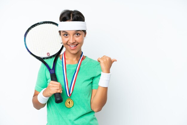 Jeune joueuse de tennis isolée sur fond blanc pointant vers le côté pour présenter un produit