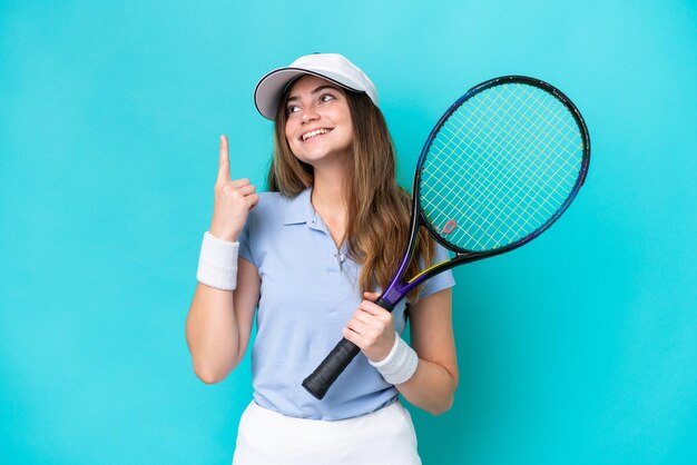 Jeune joueuse de tennis isolée sur fond bleu pointant vers une grande idée