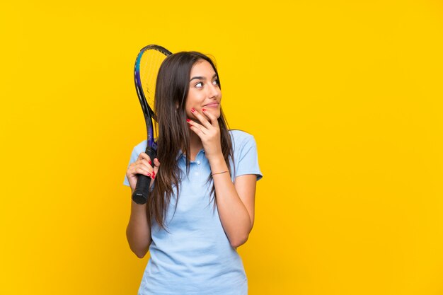 Jeune joueuse de tennis isolée sur un mur jaune, pensant à une idée