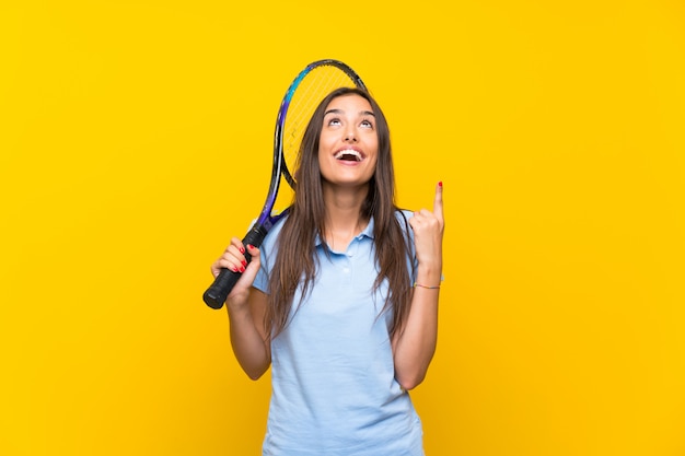 Jeune joueuse de tennis sur mur jaune isolé pointant une excellente idée