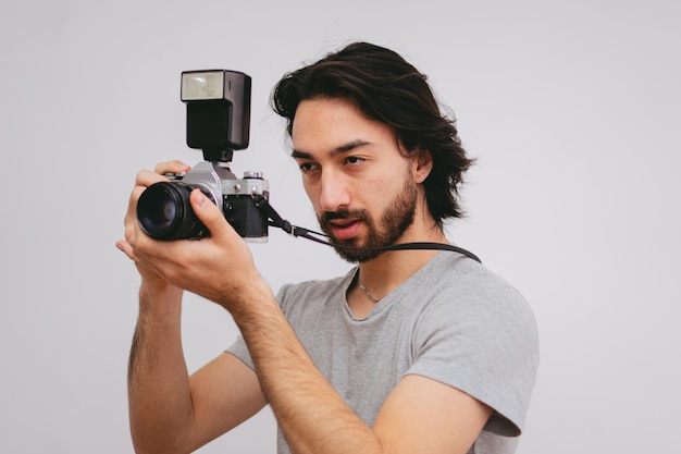 Jeune journaliste masculin latin avec une caméra analogique professionnelle aux cheveux longs