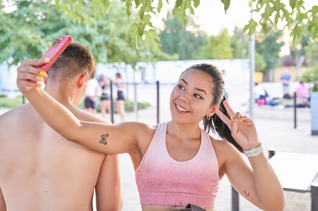 Jeune latina prenant un selfie après avoir entraîné une femme assise à côté d'un homme méconnaissable, le dos tourné