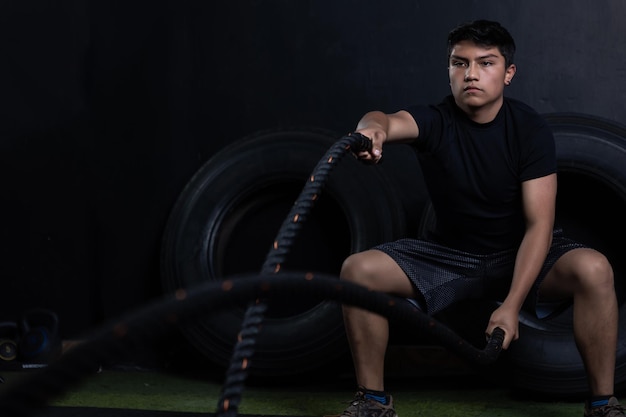 Un jeune Latino s'entraîne avec des cordes au gymnase.