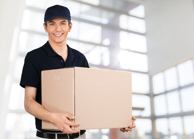 Jeune livreur en chemise noire et casquette tenant la boîte