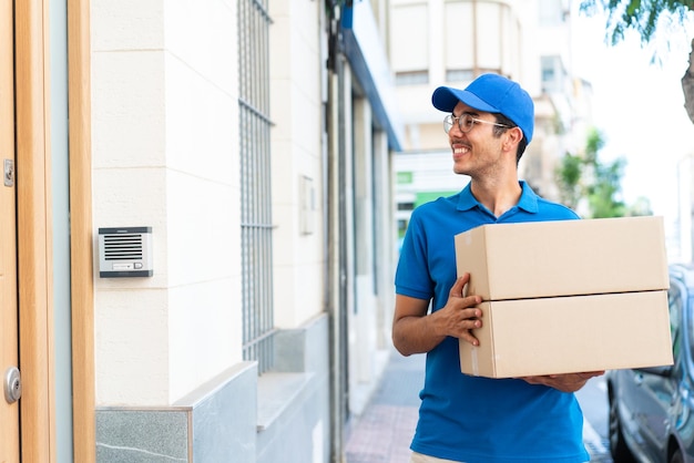 Jeune livreur à l'extérieur tenant des boîtes