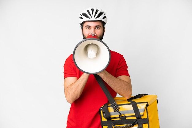 Jeune livreur avec sac à dos thermique sur fond blanc isolé criant à travers un mégaphone