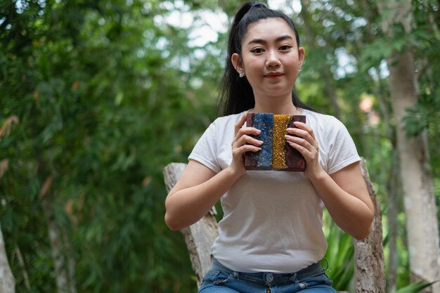 Jeune main de femme d'Asie tenant la résine époxyde avec le bâton en bois d'érable de ronce