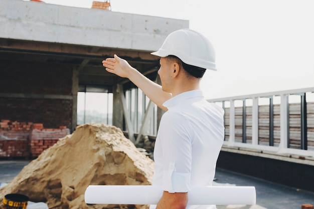 Jeune maître montrant où faire des changements de bâtiment dans la construction.