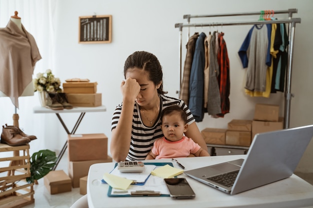 Jeune maman asiatique travaillant à domicile avec sa fille