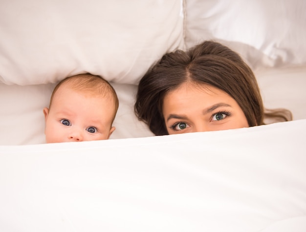 Jeune maman avec un bébé dans le lit à la maison.