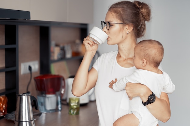 Jeune maman avec bébé s'amuser dans la cuisine à la maison