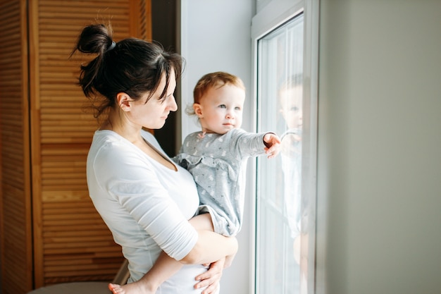 Jeune Maman, à, Dorlotez Fille, Sur, Mains, Près, Fenêtre, Chez Soi