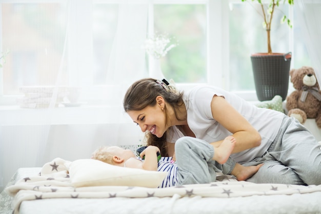 Jeune maman embrasse son bébé allongé sur le lit