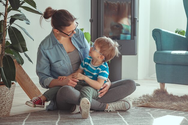 Jeune maman et enfant s'embrassant assis sur le sol à la maison