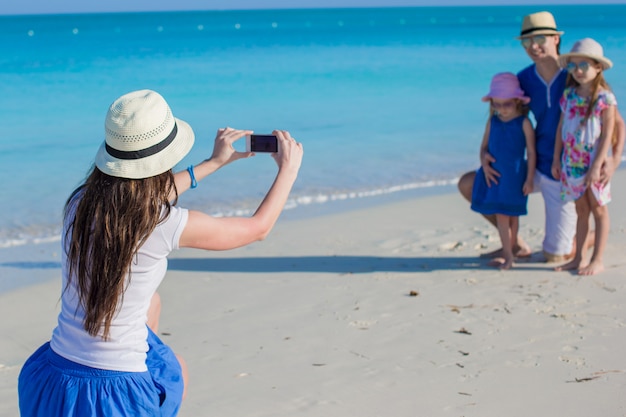 Jeune maman faisant une photo sur le téléphone de sa famille à la plage