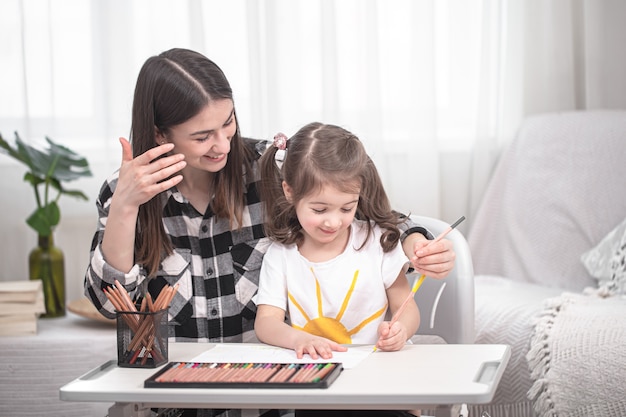 La jeune maman fait ses devoirs avec sa petite fille mignonne. Enseignement et éducation à domicile