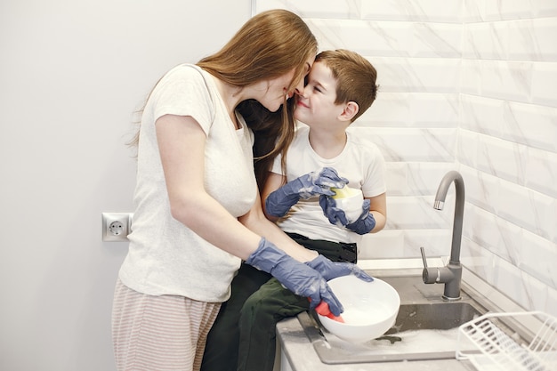 Jeune Maman Avec Un Garçon Lave La Vaisselle Dans La Cuisine.