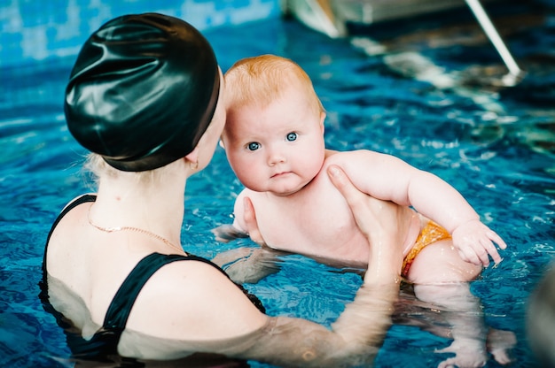 Jeune maman, instructeur de natation et heureuse petite fille dans la pataugeoire