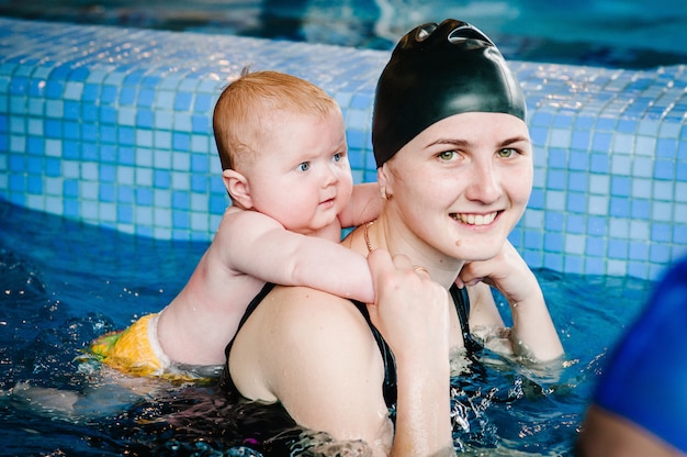 Jeune maman, instructeur de natation et heureuse petite fille dans la pataugeoire