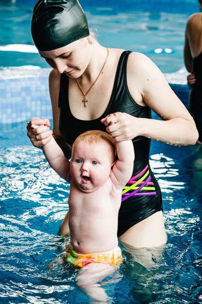 Photo jeune maman, instructeur de natation et heureuse petite fille dans la pataugeoire