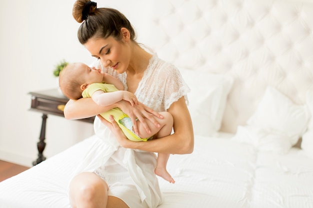 Jeune maman et jolie petite fille sur le lit