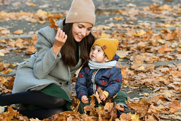 Jeune maman joue avec un petit enfant dans un parc d'automne.