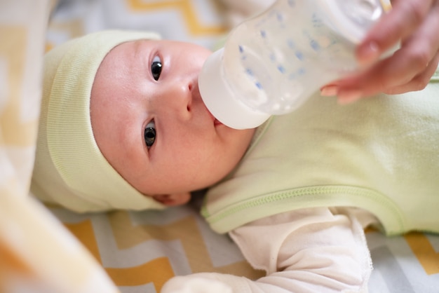 jeune maman nourrit son lait de bébé à partir d'une bouteille