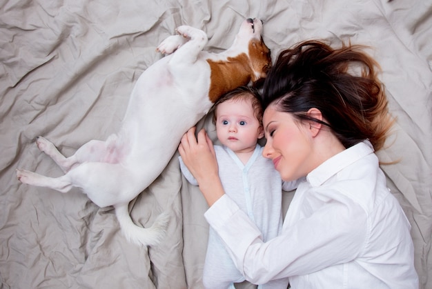 Jeune maman et un petit enfant avec chien couché sur le lit