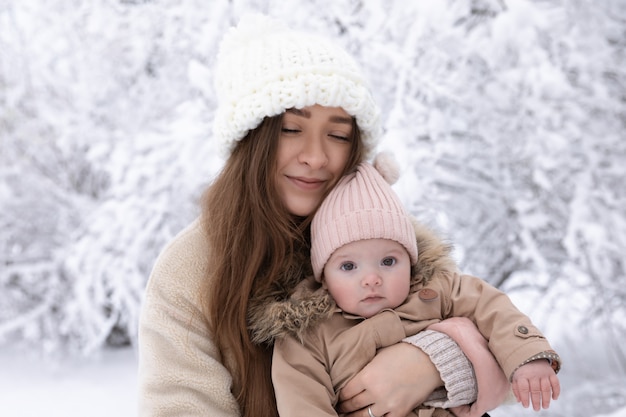 Une jeune maman avec un petit enfant joue dans la neige