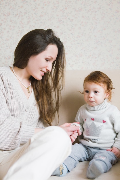 Jeune maman avec petits enfants sur les mains, assis sur le canapé. Jeune, femme, fille